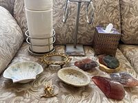 Lot displayed on patterned fabric sofa including metal toilet paper holder, woven tissue box cover, decorative soap dishes, and Soaprocks soaps.