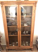 Front view of wooden china cabinet with glass doors displaying mineral and rock specimens inside.