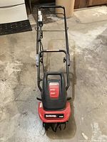 Top-down view of the red and black electric cultivator with handle and front label.