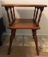 Front view of the knotty pine end table showing smooth top surface, lower shelf, and four turned legs