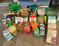 Full lot image showing various fertilizer bags, bottles, and containers arranged on the floor.