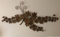 Full view of the wall decoration showing the entire piece with multiple leaves on curved stems.