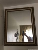 Front view of the rectangular wall mirror showing the full reflective surface and gold frame.