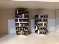 Eleven ceramic dessert bowls stacked in two groups showing the Mikasa Intaglio Arabella pattern with blue and black floral motifs on a beige background.