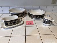 Top-down view showing the serving pieces: gravy boat with saucer, two serving bowls, jelly jar with lid and spoon on a tiled countertop with numbered card.
