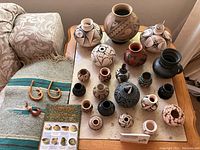 Overview of entire lot on wooden table showing pottery, runner, postcards and wood carvings