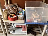 Shows the Singer Touch and Sew 626 sewing machine with multiple containers of sewing supplies and quilting books on a shelf.