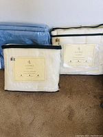 Three packaged Ralph Lauren acrylic blankets; two white with black trim, one light blue.