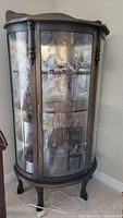Front view of oak bow-front display cabinet showing bowed glass doors and claw feet