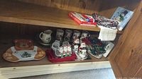 Shelf display of bear tray, Christmas mugs, napkin rings, pitcher, and fabric napkins