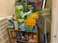 Photo of stacked cleaning supplies showing multiple Swiffer products, cleaning sprays, and other cleaning tools.