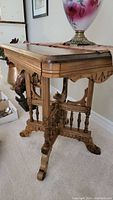 Side view of oakwood table showing X pedestal base, turned spindles, and carved apron and legs.