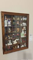 Full front view of the wooden display case showing the miniatures placed in individual compartments.