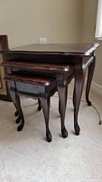 Set of three wood nesting tables stacked, showing scalloped edges and Queen Anne style legs.