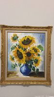 Front view of original sunflower painting in ornate gold frame.