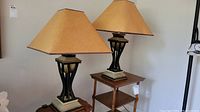Pair of table lamps with pagoda style shades, heavy bases, shown on wooden side tables.