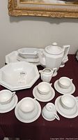 Overview of all pieces including octagonal serving bowl with lot tag, cups and saucers, teapot, gravy boat, sugar bowl, cream pitcher, and ladle on burgundy cloth.
