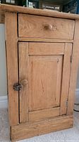 Front view of the vintage wood cabinet showing upper drawer and lower door with wooden knobs and latch closure.