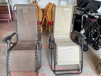 Both outdoor lounge chairs side by side in garage setting, showing frame and fabric seats