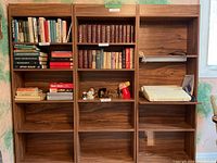 Photo showing all three wooden bookshelves side by side with some books and small items placed on shelves to demonstrate scale and shelf sizes. Shelf interiors are mostly empty here.