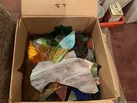 Box of assorted colored stained glass pieces including amber, green, purple, and marbled whites