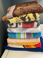 Stack of 8 beach towels showing various colors and patterns