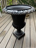 Front view of the cast iron urn-style planter showing overall shape and decorative rim