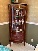Full view of display cabinet showing curved glass door, wooden finish and decorative mounts