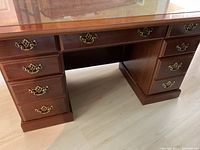 Front view showing double pedestal desk with five drawers on each side and one drawer in the middle. Desk top has a glass protective piece.