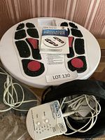 Full view of the Dr. Ho Circulation Promoter device showing foot massage pads, control unit with cables, instructional manual, and part of the carrying case.