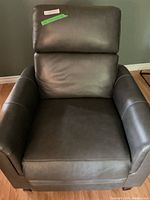 Front view of upright dark grey recliner showing padded arms and backrest