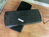 Two black GoZone exercise step platforms stacked on each other on wooden floor.