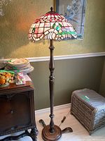 Full view of floor lamp showing stained glass shade and wooden stand near vintage side table.