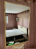 Full view of the rectangular beveled mirror hung on a wall, showing bedroom reflection.