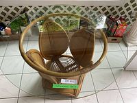 Top down view of round glass top table showing rattan petal base design and transparent surface.