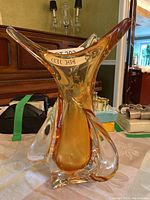 Front angle showing amber colored glass overlay with extended curved points, vase is heavy and about 12 inches tall, sitting on dining table.