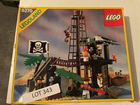 Front of box for LEGO 6270 Legoland Pirates set showing pirate hideout with lookout tower, pirate flag, and minifigures around the set.