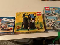 Photo showing three LEGO sets on table: 6350 pizzeria building with delivery van, 6054 medieval castle set, and an ice cream van set