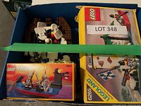 Top-down view of blue box containing three sealed LEGO set boxes and loose parts