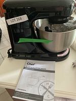Angle view of the black Master Chef stand mixer with 4.7 quart bowl and user manual in front.