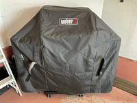 Grill covered by black Weber-branded protective cover
