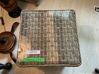 Top view showing square glass top and woven wicker surface beneath glass.