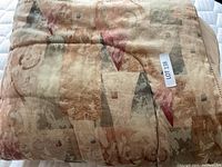 Folded queen size decorative duvet with jacquard pattern in warm tones.