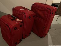 Photo showing the three red luggage pieces standing upright, highlighting size differences and expandable zippers