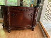 Front view of the wooden bar showing carved details and marble top.