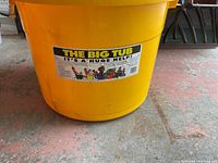 Side view of the large yellow plastic bucket label 'The Big Tub' with text and cartoon images