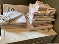Stack of assorted white and colored towels on a washing machine