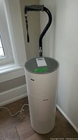 Side view of Floia Kilo Pro air purifier with cane resting behind it, showing full cylindrical shape and handle of cane.