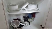 Photo of shelf with various baking and cooking items including Pyrex glass dishes, French White casserole dishes with lids, mixing bowls, strainer,and funnel.