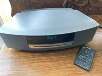 Front view of Bose Wave radio with CD tray and clock display alongside remote control